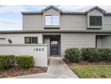 Two-story townhome with gray siding, a blue door, and well-manicured landscaping at 1903 Se 37Th Court Cir, Ocala, FL 34471