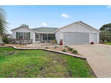 House exterior featuring a two-car garage, landscaped lawn, and a screened porch at 9203 Se 179Th Lunsford Ln, The Villages, FL 32162