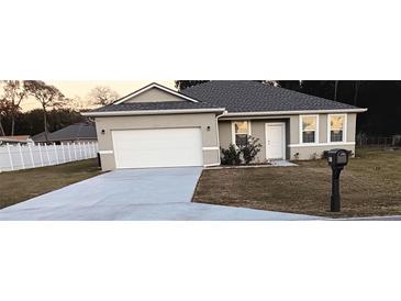 One-story house with gray roof, white garage door, and landscaped yard at 10871 Sw 62Nd Avenue Rd, Ocala, FL 34476