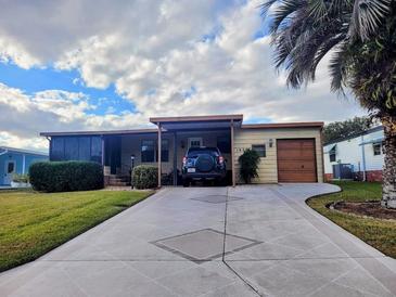 Single story home with carport and palm trees, and landscaped lawn at 1628 Bay Meadows Ln, The Villages, FL 32159