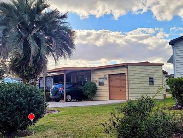 Tan single story home with carport and garage, and neatly landscaped lawn at 1628 Bay Meadows Ln, The Villages, FL 32159