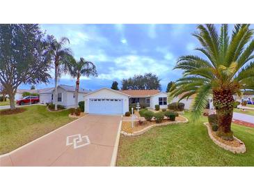 Single-story home with attached garage, landscaped yard, and palm trees at 17096 Se 96Th Chapelwood Cir, The Villages, FL 32162