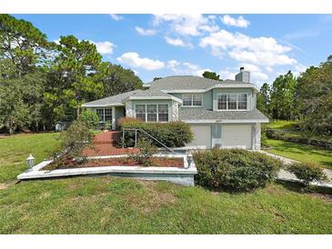 House exterior boasts a two-car garage and nicely landscaped front yard at 22777 Sw Surf Blvd, Dunnellon, FL 34431