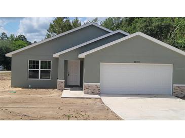 Charming single-story home featuring a gray exterior, a two-car garage, and decorative stone accents on the facade at 24300 Sw Sea Cliff Ave, Dunnellon, FL 34431