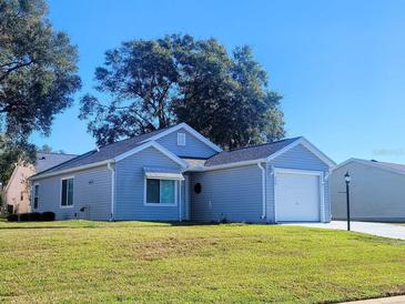 Cute one-story home with a white garage door and landscaped lawn at 529 Alcazar Ct, The Villages, FL 32159