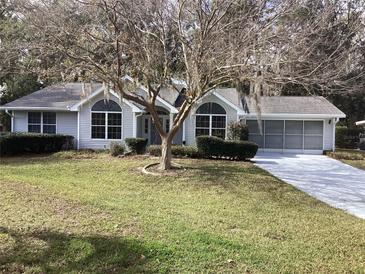 Single-story house with grey siding, landscaped lawn, and driveway at 10814 Sw 83Rd Ave, Ocala, FL 34481