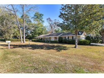 Ranch-style home with a spacious lawn and mature trees at 1105 Ne 17Th Ne Ter, Ocala, FL 34470