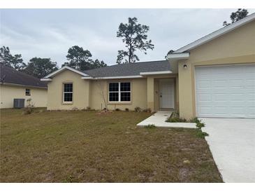 Tan one-story house with a white door and attached garage at 6189 Sw 134Th St, Ocala, FL 34473