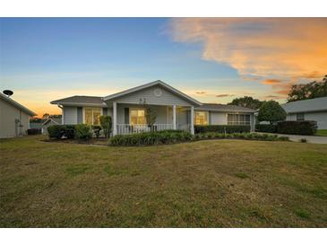 Charming single-story home with a well-manicured front yard and covered porch at sunset at 8188 Sw 108Th Loop, Ocala, FL 34481