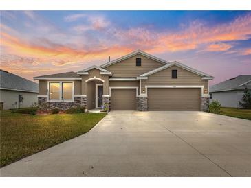 Two-story house with a three-car garage, stone accents and landscaping at 9181 Sw 49Th Ct, Ocala, FL 34476