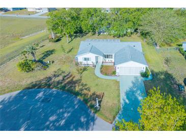 Aerial view of a well-maintained home with a spacious yard, landscaping, and driveway at 10882 Sw 62Nd Ave, Ocala, FL 34476
