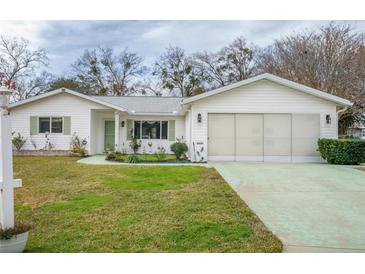 White single-story house with a two-car garage and well-maintained lawn at 10882 Sw 62Nd Ave, Ocala, FL 34476