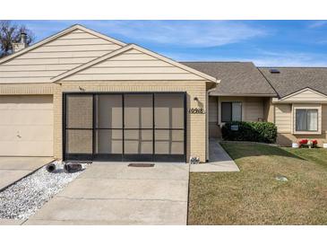 Tan brick condo with screened porch, 1 car garage, and landscaped lawn at 10918 Se 50 Ave, Belleview, FL 34420