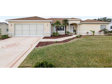 Tan one-story house with palm trees and landscaped yard at 13560 Se 90Th Ct, Summerfield, FL 34491