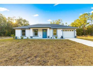 Newly constructed home with gray roof, white exterior, and blue front door at 14108 Se 42Nd Ter, Summerfield, FL 34491