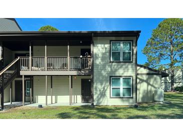 Tan two-story condo building with private deck and stairs at 23104 Sandalwood Dr # 104, Wildwood, FL 34785