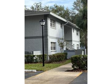 Exterior view of a condo building with walkway and landscaping at 571 Midway Trak # J103, Ocala, FL 34472