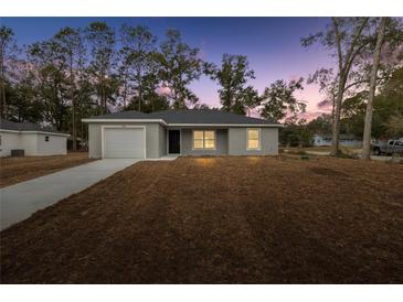 Newly constructed home with gray exterior, attached garage, and a well-manicured lawn at 6088 Nw 57Th Ave, Ocala, FL 34482