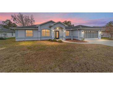 House exterior featuring gray siding, landscaping, and a screened garage at 10628 Sw 74Th Ave, Ocala, FL 34476