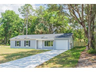 Newly constructed home with gray siding, white garage door, and a paved driveway at 13099 Ne 7 Loop, Silver Springs, FL 34488