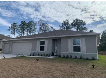 Gray house with a two-car garage, landscaping, and a small front yard at 15155 Sw 52 Cir, Ocala, FL 34473