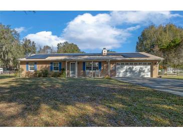 Ranch-style home with solar panels, a two-car garage, and a spacious yard at 2645 Se 162Nd Place Rd, Summerfield, FL 34491