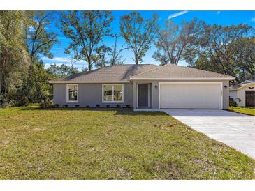 Newly constructed home with gray siding, white garage door, and a well-manicured lawn at 7084 Se 124 St, Belleview, FL 34420