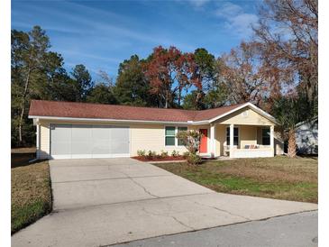 Cute yellow house with red door, screened garage, and landscaped yard at 8623 Sw 108Th Place Rd, Ocala, FL 34481