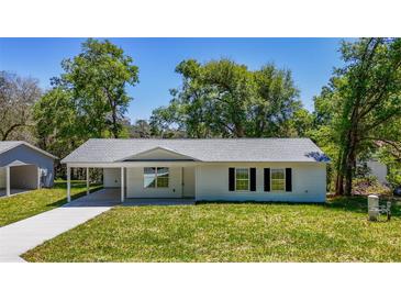 Charming single-story home featuring a covered carport and a freshly landscaped front yard at 16434 Se 57 Pl, Ocklawaha, FL 32179
