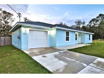 Light blue house with white garage door, driveway, and landscaped lawn at 4562 Sw Hyacinth Ct, Dunnellon, FL 34431