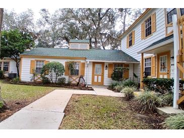 Front view of charming house with green roof and yellow accents at 7990 Midway Drive Ter # M102, Ocala, FL 34472