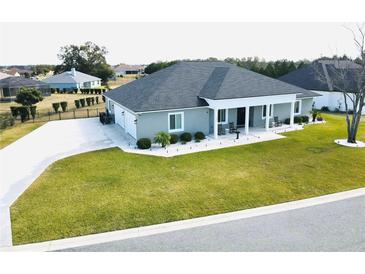 Gray house with a three-car garage and rocking chairs on the porch at 9645 Se 61St Ter, Belleview, FL 34420