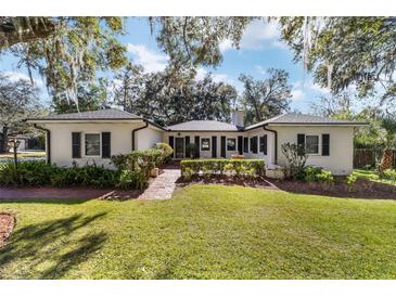 White brick home with black shutters, landscaping, and a spacious lawn at 1758 Se 7Th St, Ocala, FL 34471