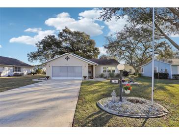 Tan one-story house with a screened-in garage and landscaped yard at 1904 Tweed Ct, Leesburg, FL 34788