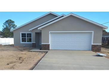 Newly constructed home with a gray exterior, white garage door, and stone accents at 5 Pine Course Loop, Ocala, FL 34472