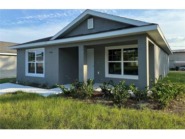 Gray house with a white door, landscaping, and a grassy yard at 6574 Se 108Th Ln, Belleview, FL 34420