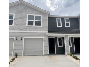 Stylish two-story townhome featuring a one-car garage and modern gray color scheme at 6590 Sw 81St Loop, Ocala, FL 34476