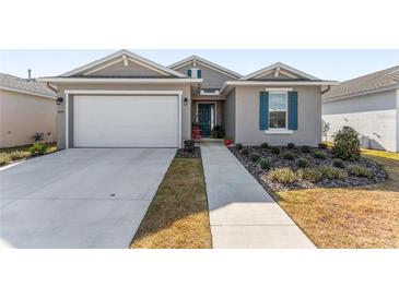 Single-story home with gray siding, white garage door, and landscaping at 7094 Sw 60Th Ln, Ocala, FL 34474