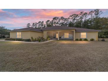 One-story house with screened porch, landscaped yard, and sunset view at 21590 Sw 84Th Loop, Dunnellon, FL 34431