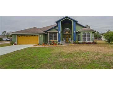 Green house with yellow garage door, landscaping, and a spacious yard at 2831 Sw 139Th St, Ocala, FL 34473