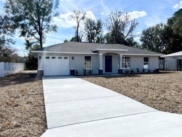 Newly constructed one-story home with gray exterior, white garage door, and landscaping at 4310 Se 139Th Pl, Summerfield, FL 34491