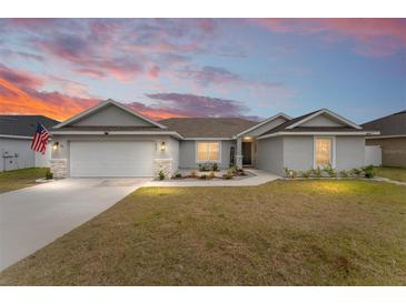 Single-story home with gray siding, attached garage, and landscaped yard at 5050 Sw 91 Pl, Ocala, FL 34476