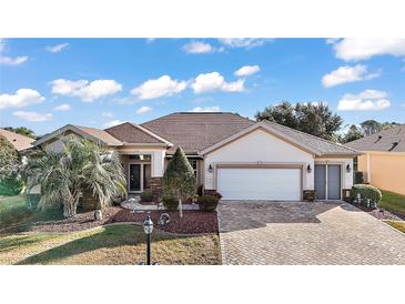 Inviting single-story home with manicured landscaping, paver driveway, and an attached two-car garage at 13077 Se 86 Ct, Summerfield, FL 34491