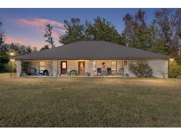 Brick ranch house with a large front porch and expansive lawn at 2821 Se 80Th St, Ocala, FL 34480