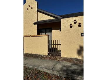 Tan stucco exterior of home with a small gate and walkway at 52 Pine Trak # G 104, Ocala, FL 34472