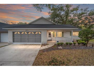 Brick ranch home with screened porch, 2-car garage, and mature landscaping at 8851 Sw 92Nd Pl # E, Ocala, FL 34481