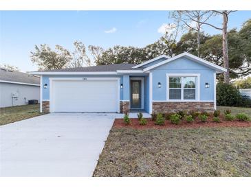 Newly built home with light blue exterior, white garage door, and stone accents at 13824 Se 42 Ave, Summerfield, FL 34491