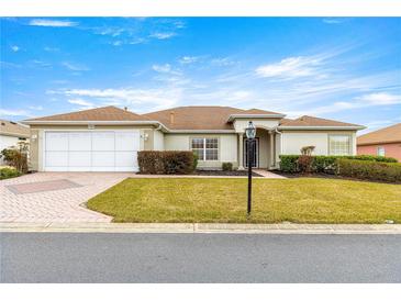 Single-story house with a two-car garage and landscaped lawn at 13957 Se 86Th Cir, Summerfield, FL 34491