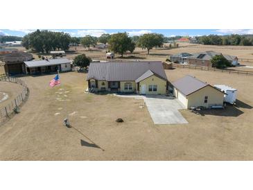 Aerial view of a ranch-style home with large lot, detached garage, and fenced pastures at 14130 Sw 8Th Ave, Ocala, FL 34473