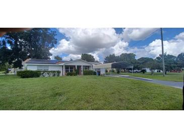 Ranch-style home with carport, solar panels, and a spacious lawn at 5235 Se 107Th St, Belleview, FL 34420